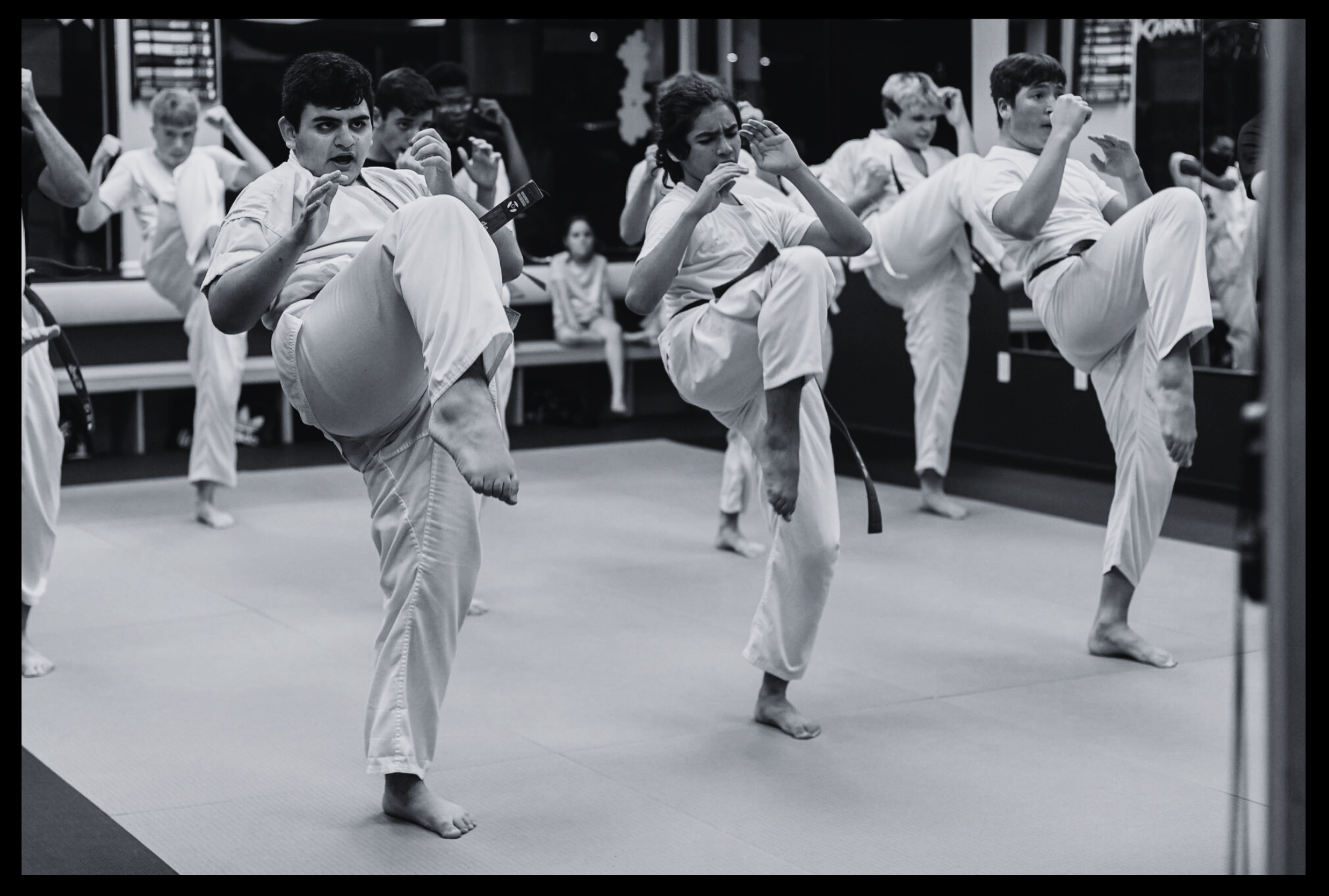 Photo of karate class students wearing gis and preparing to kick