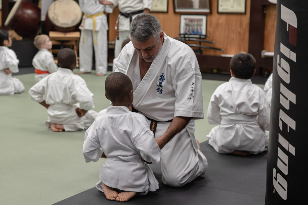 Sensei Omar kneeling in front of karate student in dojo