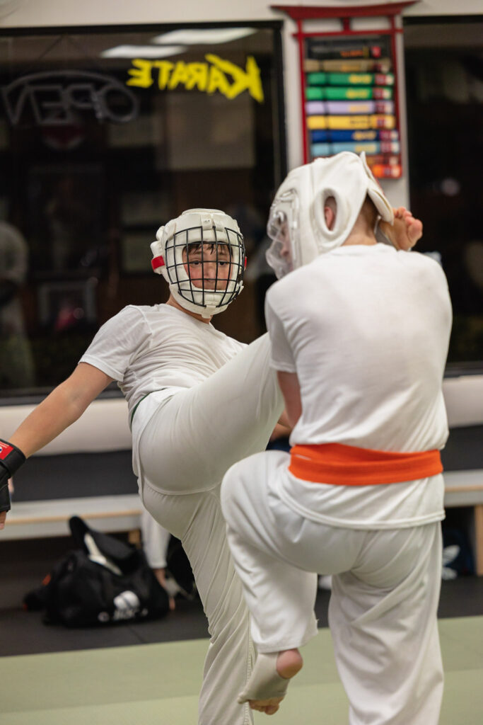 Two students sparring wearing karate gear in dojo